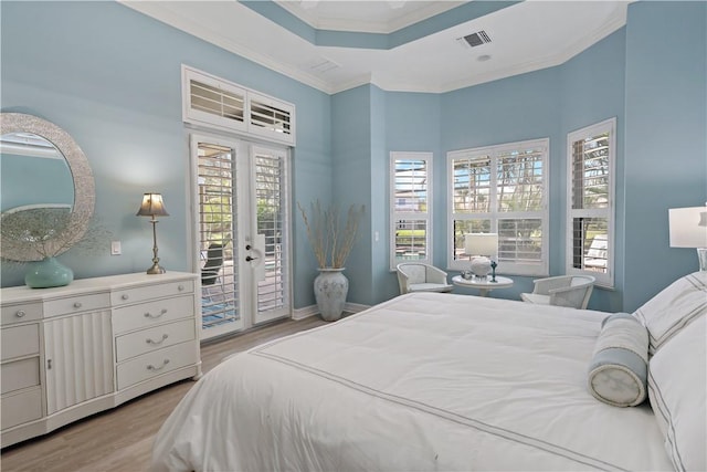 bedroom with visible vents, light wood-style flooring, access to outside, a tray ceiling, and crown molding