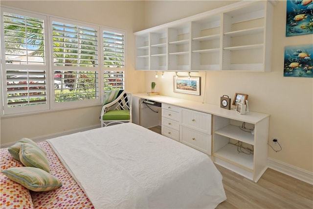 bedroom featuring light wood finished floors, built in desk, and baseboards