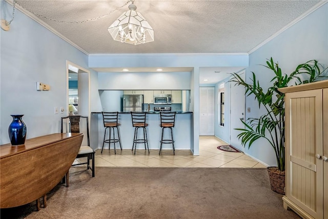 5 Plantation Dr Unit 206, Vero Beach, FL 32966 - kitchen featuring stainless steel appliances, a chandelier, ornamental molding, light tile patterned floors, and a textured ceiling