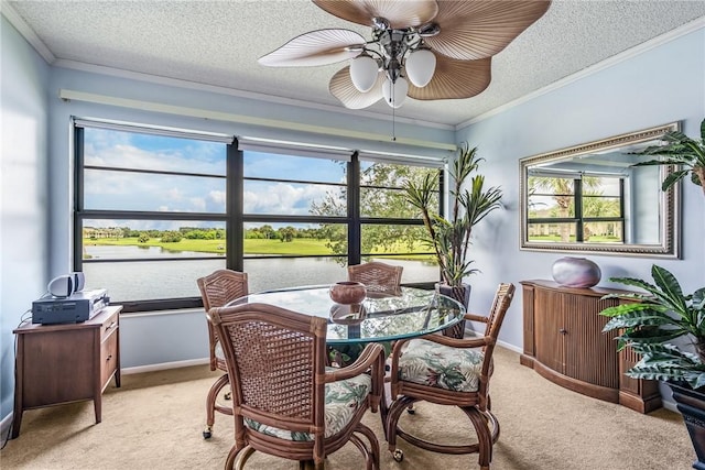 dining room with a water view, crown molding, ceiling fan, a textured ceiling, and light colored carpet