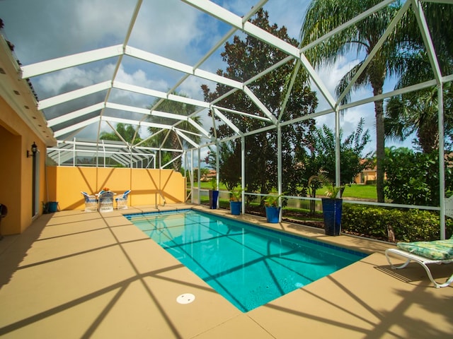 view of pool with a patio area and glass enclosure