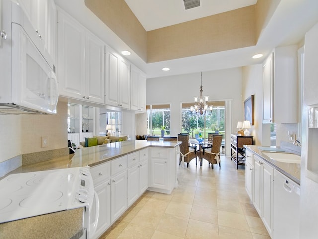 kitchen with pendant lighting, white appliances, kitchen peninsula, and white cabinets