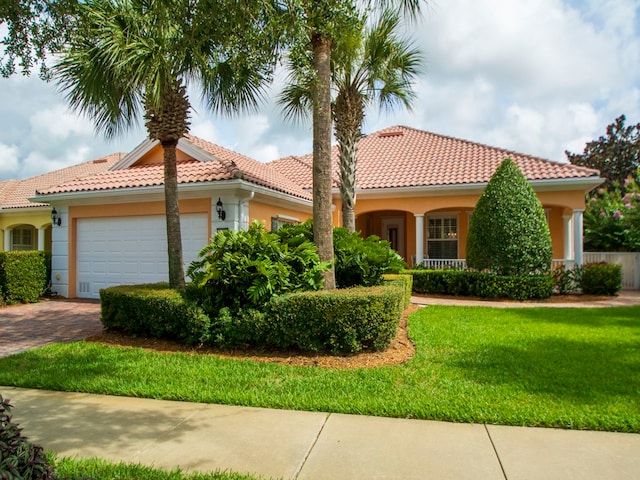 mediterranean / spanish home featuring a garage and a front lawn