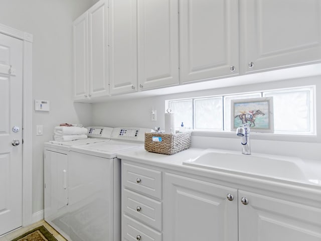 laundry area with sink, washing machine and dryer, and cabinets