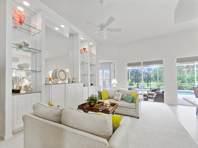 living room featuring light tile patterned flooring, ceiling fan, and built in shelves