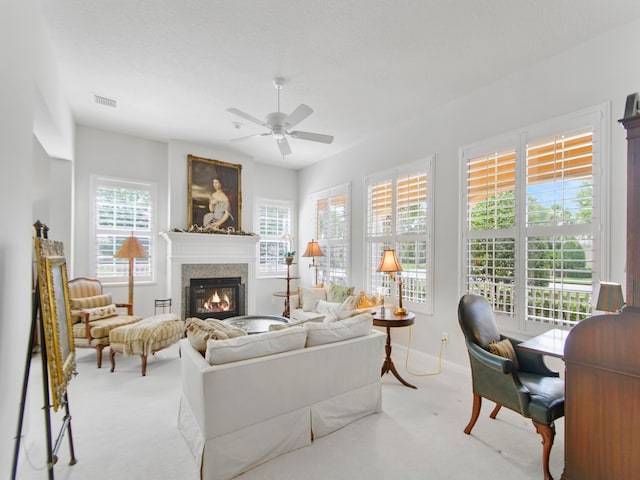 living room featuring ceiling fan, light colored carpet, and a textured ceiling