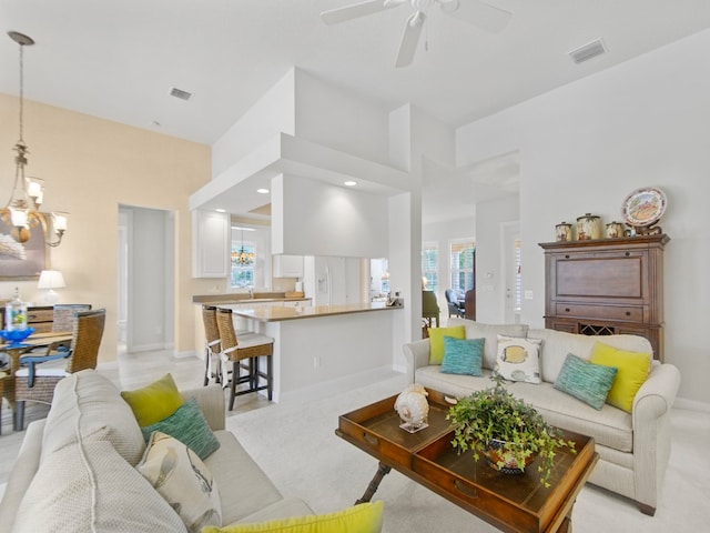 living room featuring ceiling fan with notable chandelier, light carpet, and a wealth of natural light