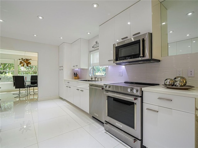 kitchen with a sink, stainless steel appliances, light countertops, modern cabinets, and backsplash