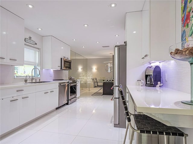 kitchen with modern cabinets, a sink, stainless steel appliances, white cabinets, and decorative backsplash