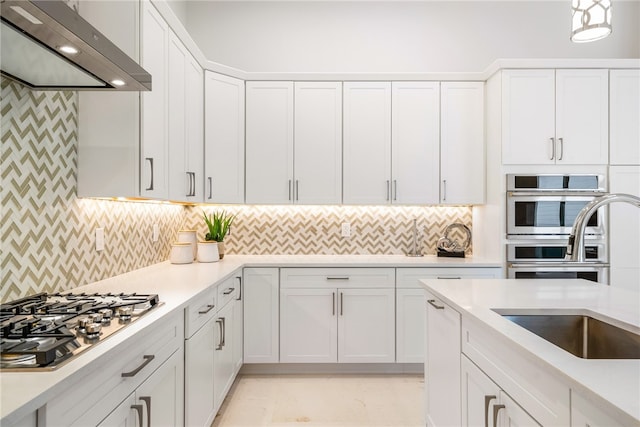 kitchen with stainless steel appliances, white cabinetry, sink, ventilation hood, and decorative backsplash