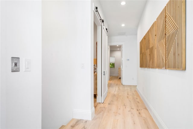 hall featuring a barn door and light hardwood / wood-style flooring