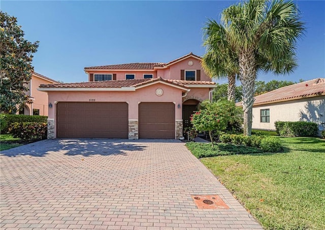 mediterranean / spanish home featuring a garage and a front yard