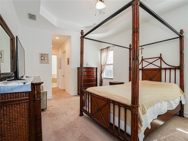 bedroom featuring ceiling fan, light colored carpet, and ensuite bath