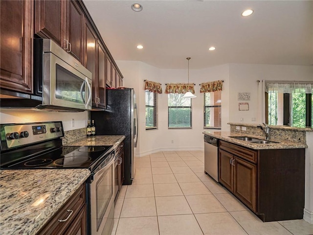 kitchen featuring hanging light fixtures, sink, light stone counters, and stainless steel appliances