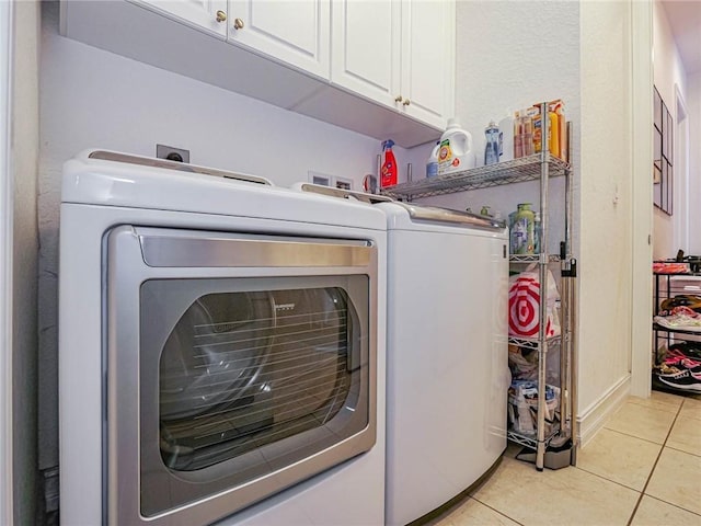 laundry room with cabinets, light tile patterned floors, and separate washer and dryer