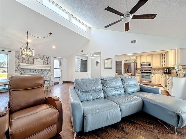 living room with visible vents, a fireplace, lofted ceiling, and wood finished floors