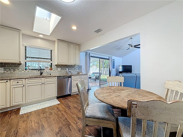 kitchen with visible vents, dark wood finished floors, a sink, stainless steel dishwasher, and tasteful backsplash