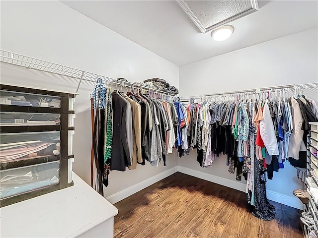 walk in closet featuring attic access and wood finished floors