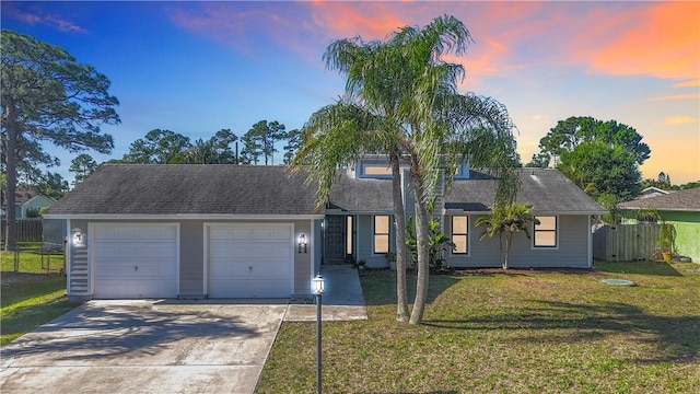 view of front of home featuring a garage, driveway, a front yard, and fence