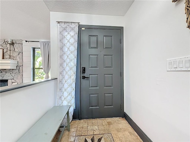 foyer entrance featuring a textured ceiling and baseboards