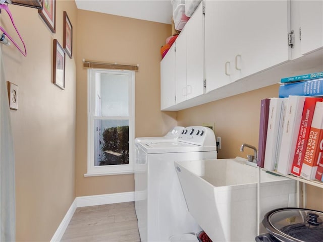 clothes washing area featuring cabinets, independent washer and dryer, light hardwood / wood-style floors, and sink