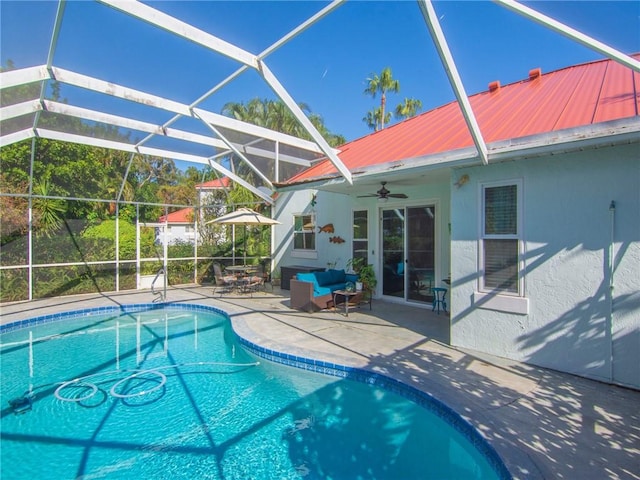 view of swimming pool featuring glass enclosure, ceiling fan, and a patio area