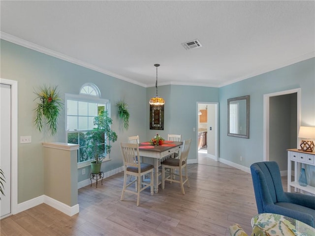 dining space with crown molding and light wood-type flooring