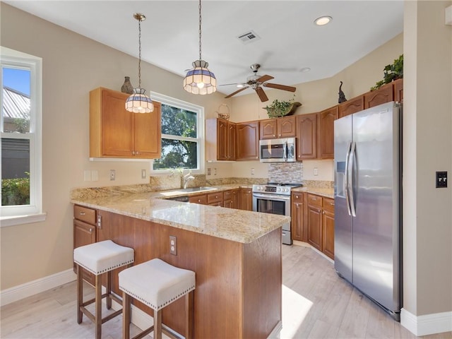 kitchen with hanging light fixtures, a breakfast bar area, light hardwood / wood-style floors, kitchen peninsula, and stainless steel appliances