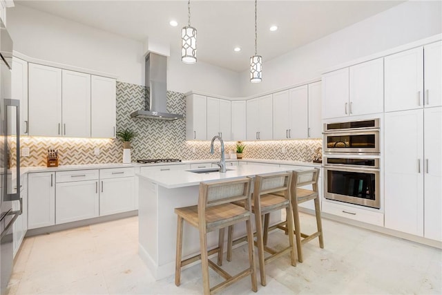 30 Strand Dr, Vero Beach, FL 32963 - kitchen with wall chimney exhaust hood, double oven, gas stovetop, light countertops, and a center island with sink