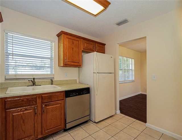 kitchen with visible vents, a sink, freestanding refrigerator, light tile patterned floors, and dishwasher