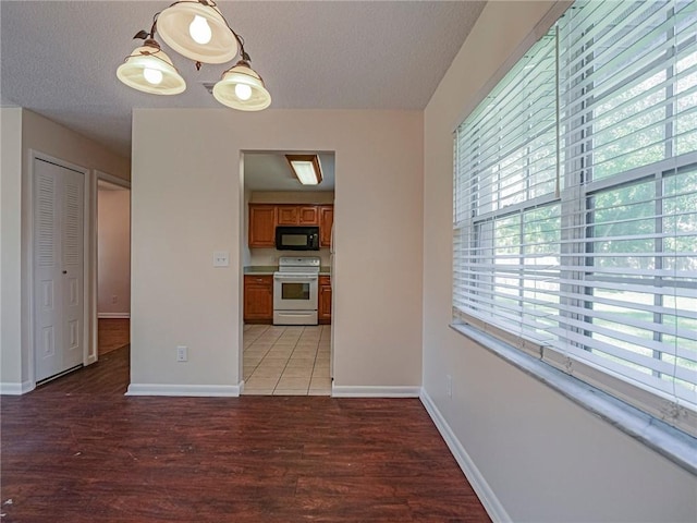 unfurnished dining area with light wood-type flooring, baseboards, and a textured ceiling