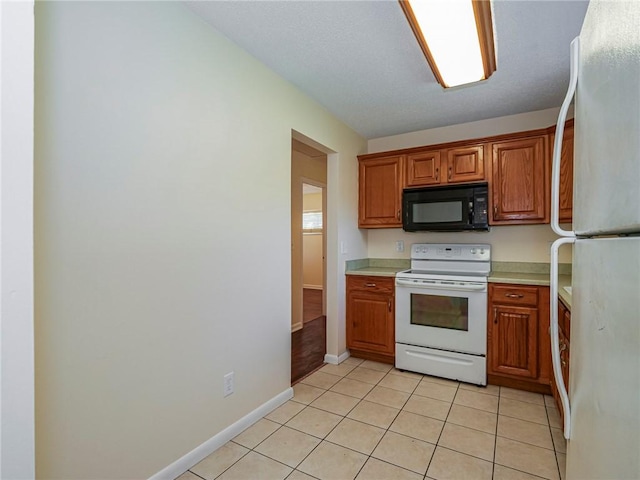 kitchen with white appliances, light tile patterned floors, light countertops, and brown cabinets