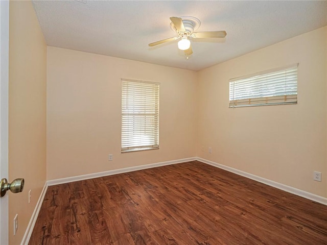 spare room with dark wood finished floors, a ceiling fan, baseboards, and a textured ceiling