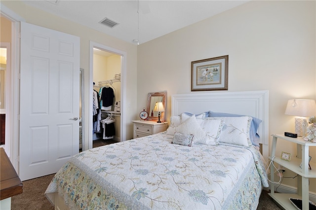 bedroom with dark carpet, a walk in closet, and a closet