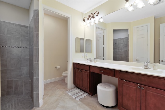 bathroom featuring a tile shower, tile patterned flooring, vanity, and toilet