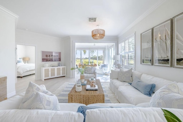 living room with visible vents, wood finished floors, baseboards, and ornamental molding