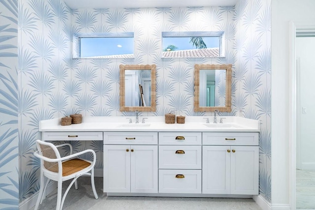 bathroom featuring wallpapered walls, double vanity, baseboards, and a sink