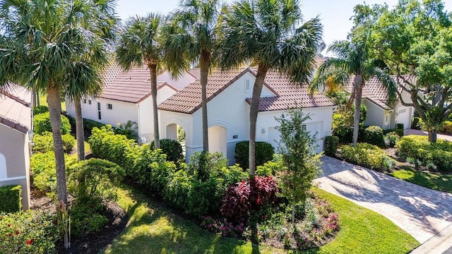 mediterranean / spanish-style home with decorative driveway, stucco siding, an attached garage, and a tile roof