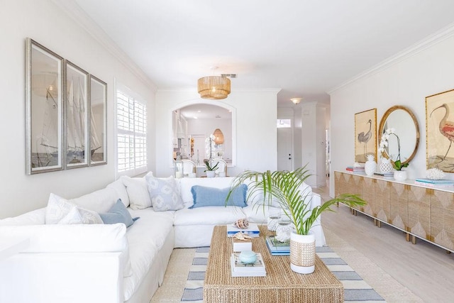 living room featuring arched walkways, visible vents, wood finished floors, and ornamental molding