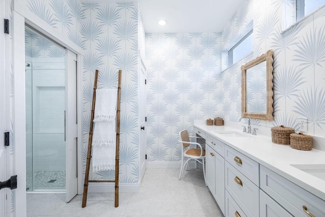 bathroom with wallpapered walls, a stall shower, baseboards, and a sink