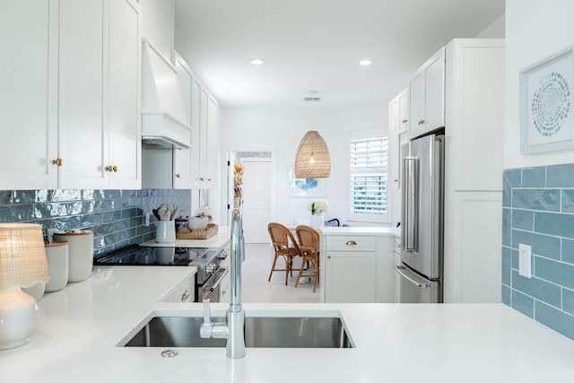 kitchen with light countertops, custom range hood, white cabinets, appliances with stainless steel finishes, and pendant lighting