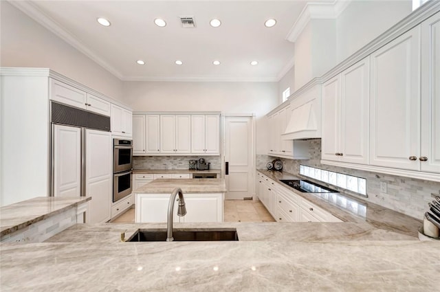 kitchen featuring sink, premium range hood, paneled built in fridge, light stone countertops, and white cabinets