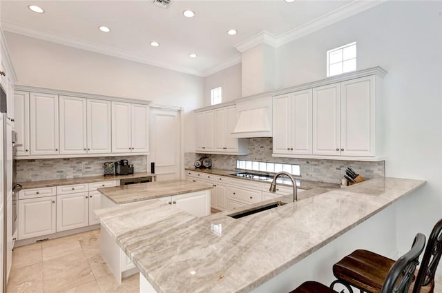 kitchen with white cabinetry, sink, a kitchen breakfast bar, and kitchen peninsula