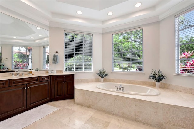 bathroom with a relaxing tiled tub, a tray ceiling, and a wealth of natural light