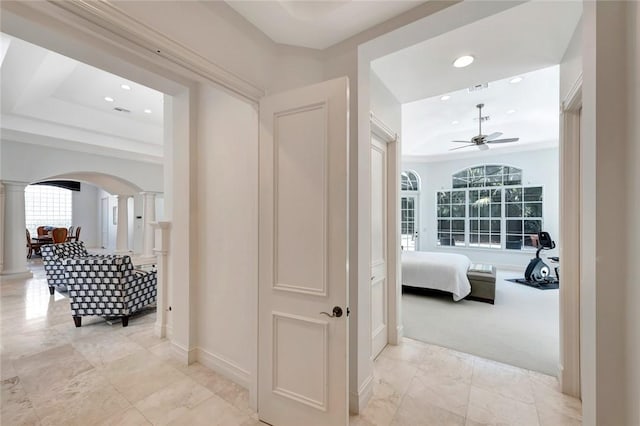 corridor with ornate columns and a tray ceiling