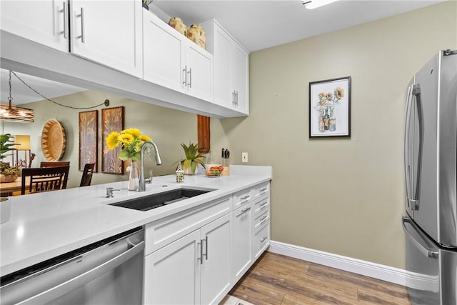 kitchen featuring a sink, stainless steel appliances, light countertops, and white cabinetry