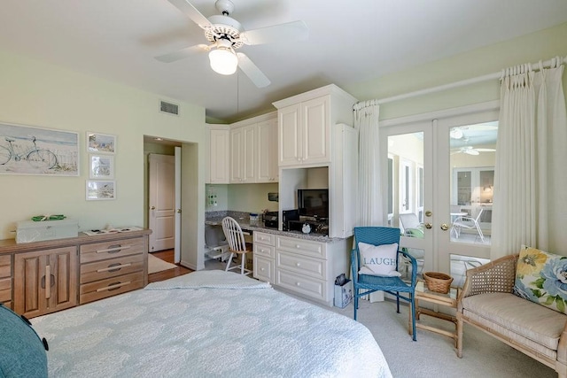bedroom featuring visible vents, light colored carpet, built in desk, french doors, and a ceiling fan