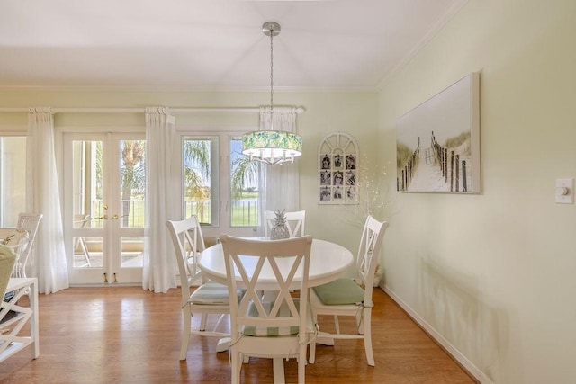 dining area with crown molding, an inviting chandelier, french doors, and wood finished floors