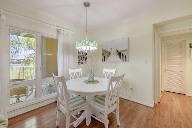 dining space with crown molding, baseboards, a chandelier, and light wood-type flooring