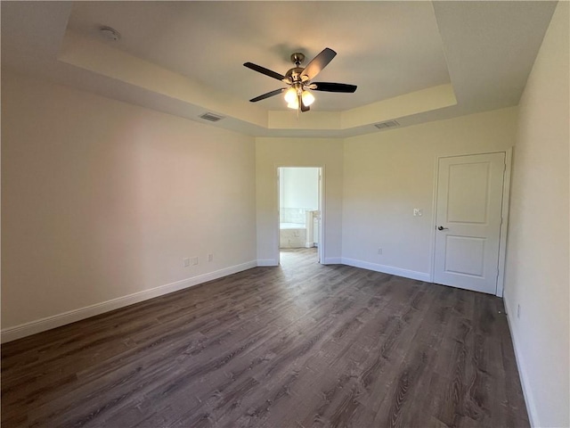 spare room with ceiling fan, dark hardwood / wood-style flooring, and a tray ceiling